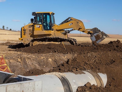 Cat 973 track loader digging near pipe in trench
