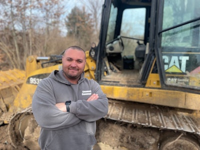 Marcus Linaweaver standing in front of a Caterpillar dozer