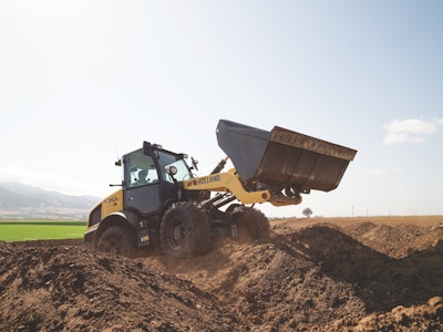 New Holland W70C compact wheel loader raising dirt filled bucket