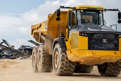 Deere autonomous 460E-II articulated dump truck with Deere excavator in background