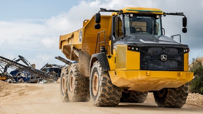Deere autonomous 460E-II articulated dump truck with Deere excavator in background