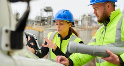 woman man in construction PPE on construction site looking at tablet
