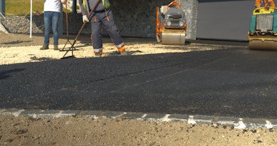stock image workers raking newly placed asphalt on driveway