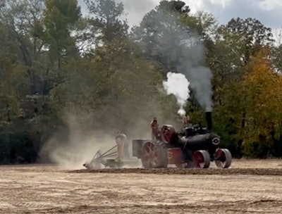 antique Sawyer-Massey steam -tractor blowing steam smoke while plowing