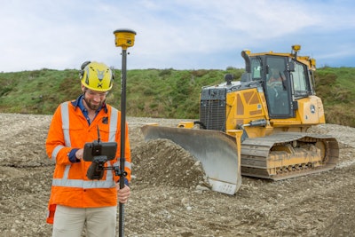 Construction worker using Trimble Works technology with a Deere bulldozer