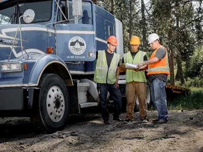 three men work outside a truck