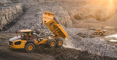 Volvo A40 articulated dump truck dumping rocks in gravel pit