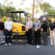 men gathered around a volvo ce compact excavator