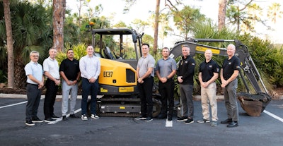 men gathered around a volvo ce compact excavator