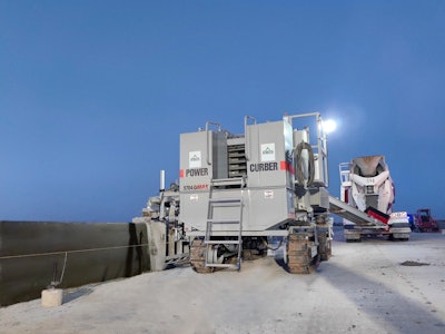 Power Curber 5704-D slipform paver pouring concrete barrier wall on highway under construction