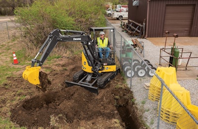 Deere 30 PTier excavator digging hole beside fence