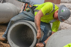 Construction worker applying a seal to a concrete pipe