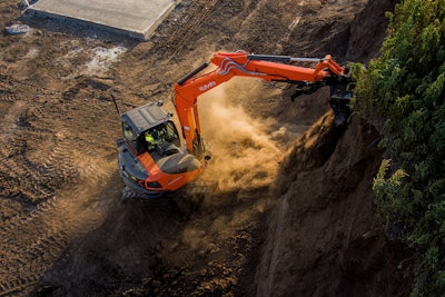 Kubota KX080 excavator digging with bucket extended high up on dirt wall