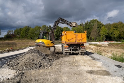 MECALAC 9MWR excavator loading truck with dirt