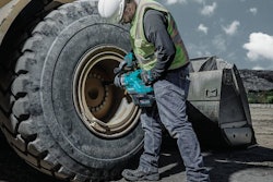 worker in hard hat using makita impact wrench on wheel loader tire