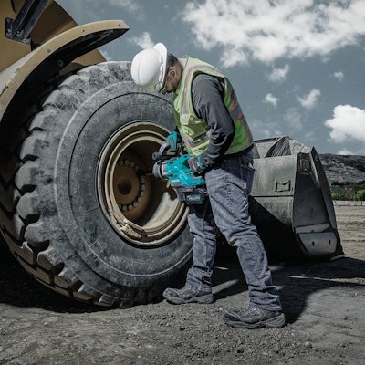 worker in hard hat using makita impact wrench on wheel loader tire