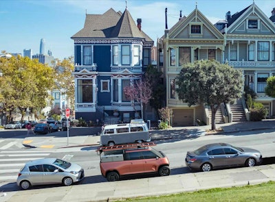 orange electric telo mt1 pickup truck parked on street across San Francisco row houses
