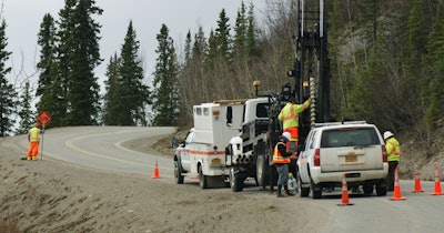 men drill test holes along a road