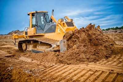 large yellow dozer pushing large mound of dirt