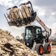 a bobcat skid steer lifting rocks