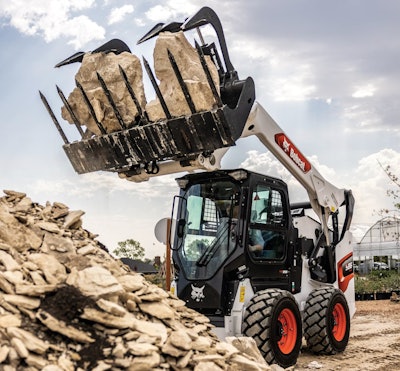 a bobcat skid steer lifting rocks