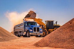 blue kenworth dump truck being loaded with dirt by wheel loader