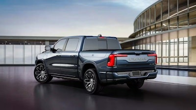 dark colored 2026 Ramcharger EV pickup truck in front of glass building