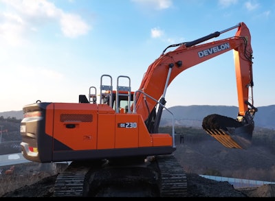 Develon DX230 excavator digging dirt on hilltop