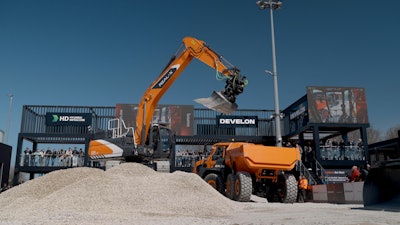 Autonomous truck loading with a DX225LC-7 excavator was showcased at Develon's Bauma 2025 booth. HD Hyundai XiteSolution, the holding company for HD Hyundai Infracore and Develon, in collaboration with Gravis Robotics AG, has signed an agreement with Holcim Inc., a building materials supplier, for the development and commercialization of autonomous technology designed to enhance productivity and improve safety in quarry operations and confined material handling applications.