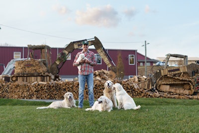 Josh Crawford, owner of Cashiers Firewood, with his Takeuchi compact excavator and compact track loader made out of logs – and his five golden retrievers that are always with him.