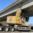 The excavator, a Caterpillar 323, was being hauled with its boom raised when it struck the bridge.