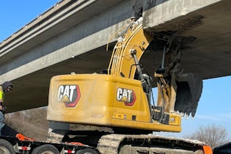 The excavator, a Caterpillar 323, was being hauled with its boom raised when it struck the bridge.