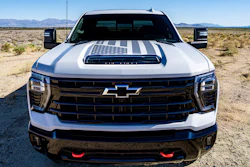 White Chevrolet heavy-duty pickup truck with American flag hood graphic, parked in a desert landscape