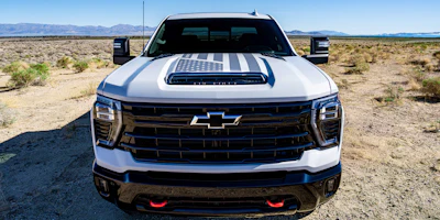 White Chevrolet heavy-duty pickup truck with American flag hood graphic, parked in a desert landscape