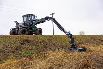 Green and black logging excavator positioned on grassy terrain with extended mechanical arm