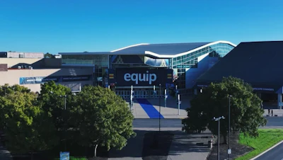 Modern glass conference center with 'Equip' signage and blue entrance walkway