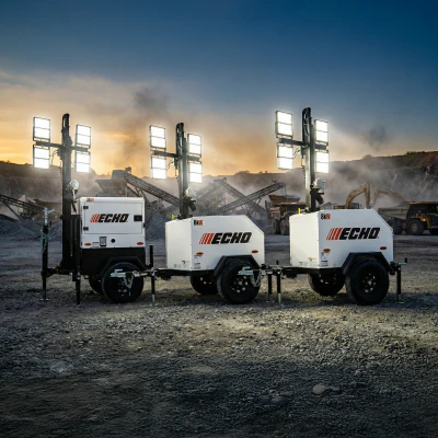 Three ECHO portable light towers with LED lighting arrays positioned on a construction site at sunset