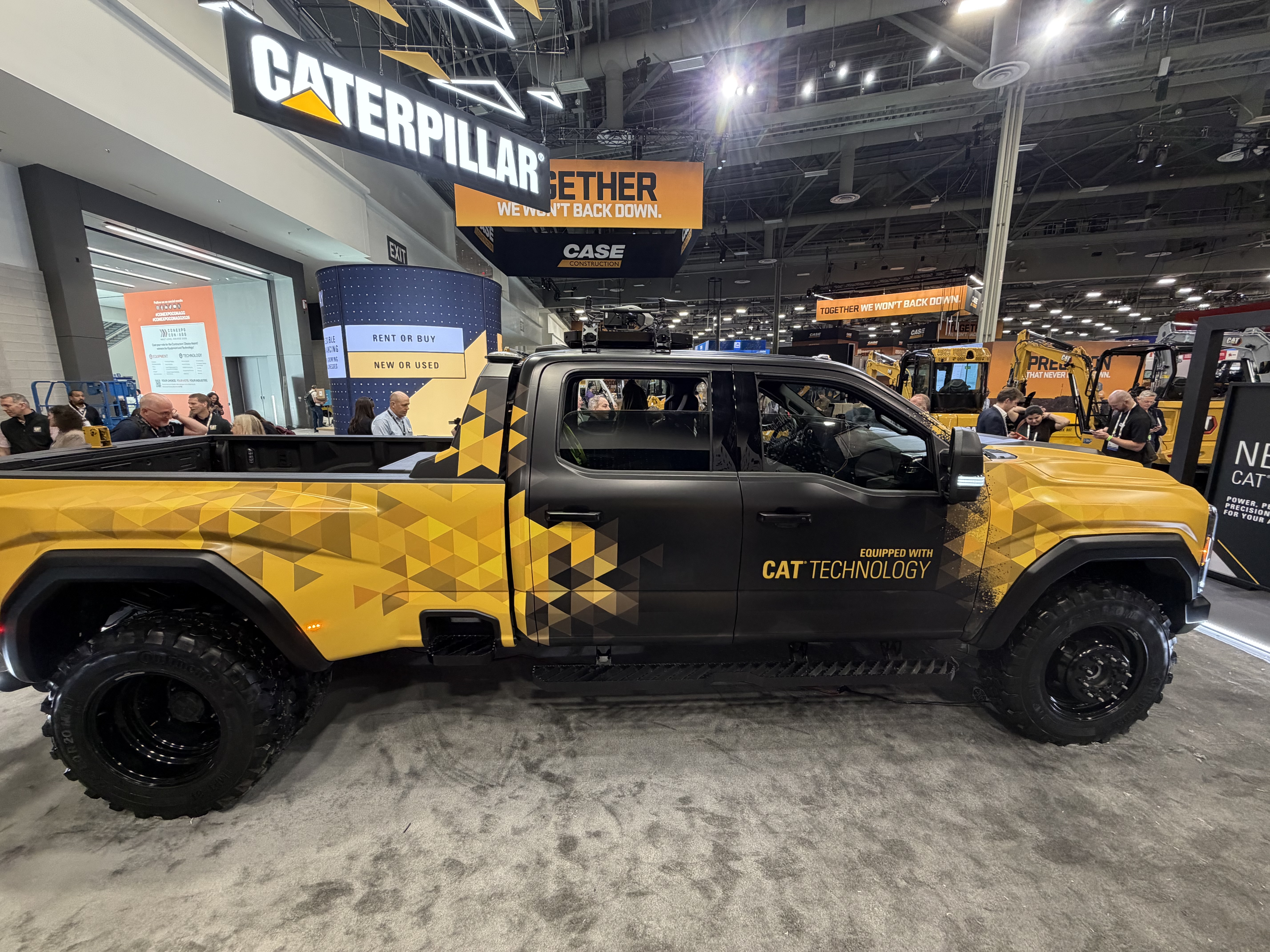 Yellow and black Caterpillar branded pickup truck on display at industrial trade show