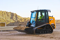 JCB 250T compact tracked loader with operator in quarry setting surrounded by aggregate piles