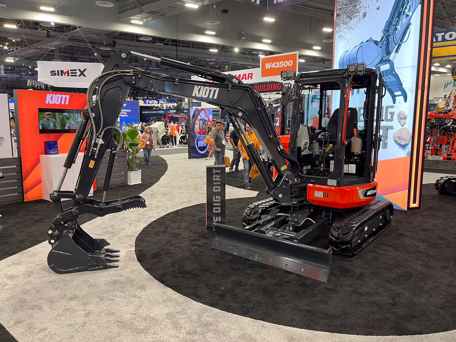 Red and black compact excavator with hydraulic arm on display at industrial trade show booth