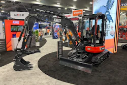Red and black compact excavator with hydraulic arm on display at industrial trade show booth