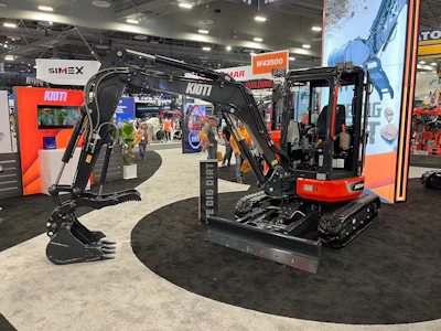Red and black compact excavator with hydraulic arm on display at industrial trade show booth