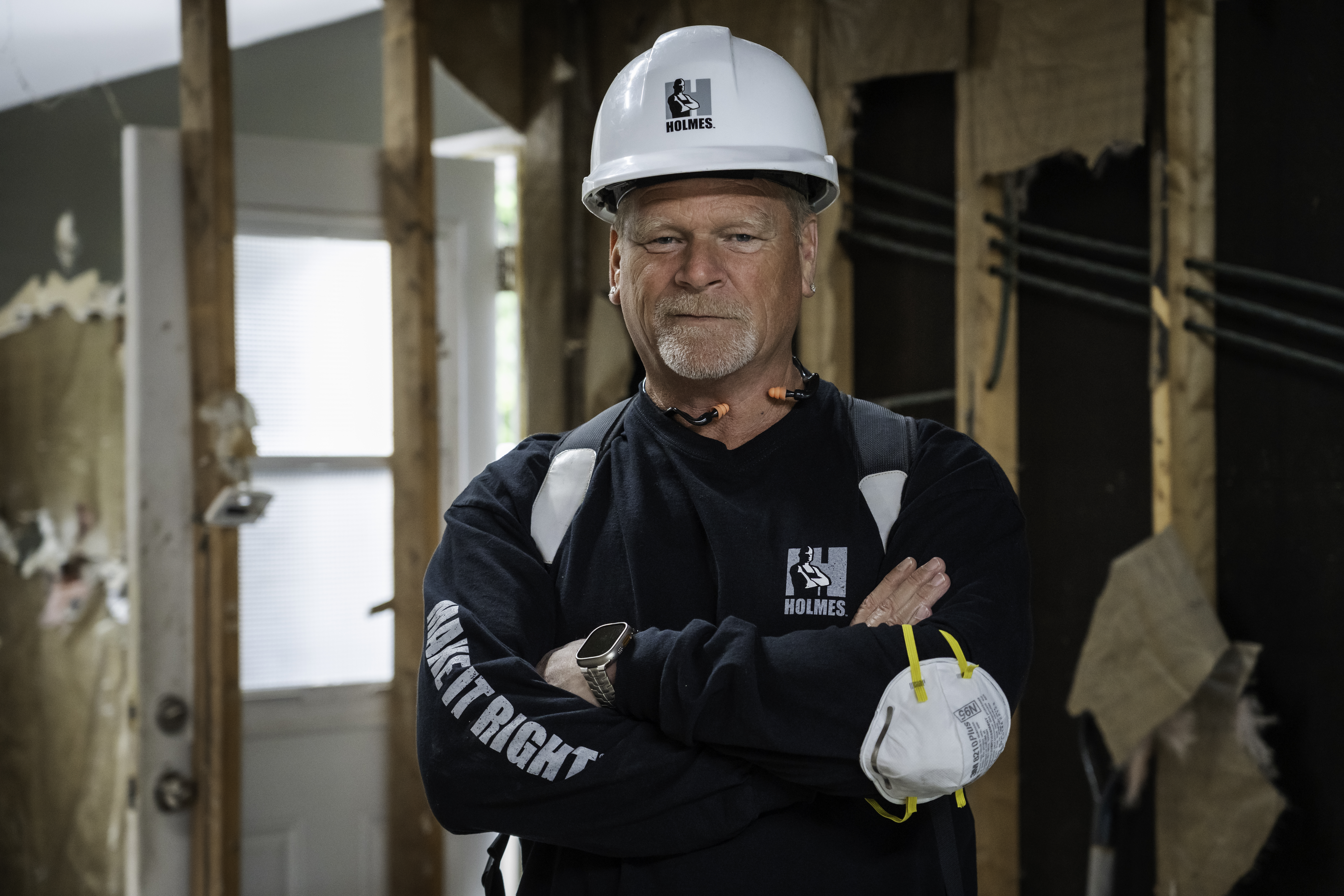 Construction worker in white hard hat and navy Holmes work jacket standing in unfinished building interior