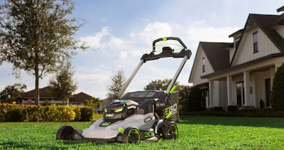 EGO Power+ electric lawn mower on manicured lawn with suburban home and landscaping in background