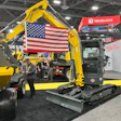 Yellow Takeuchi excavator with American flag at construction equipment trade show booth