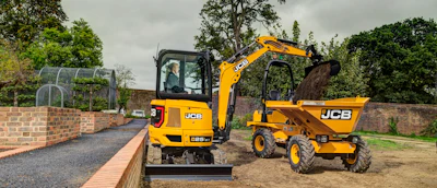 Yellow JCB mini excavator and dumper truck on a construction site with brick wall and landscaping
