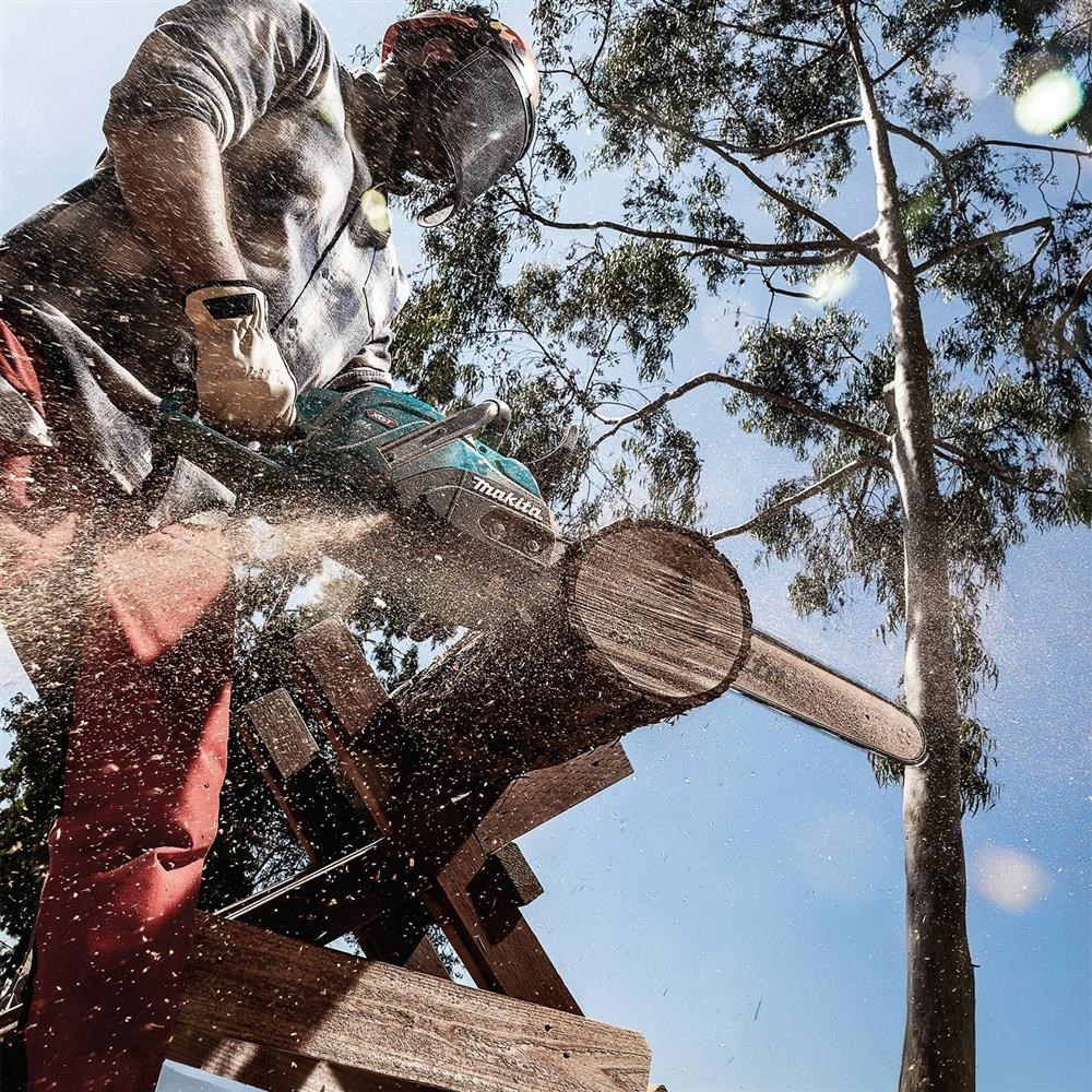 Wooden chainsaw sculpture of a person's head using a Makita chainsaw among eucalyptus trees