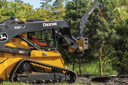 Yellow John Deere 335 skid steer loader with articulated boom arm in outdoor landscaping setting