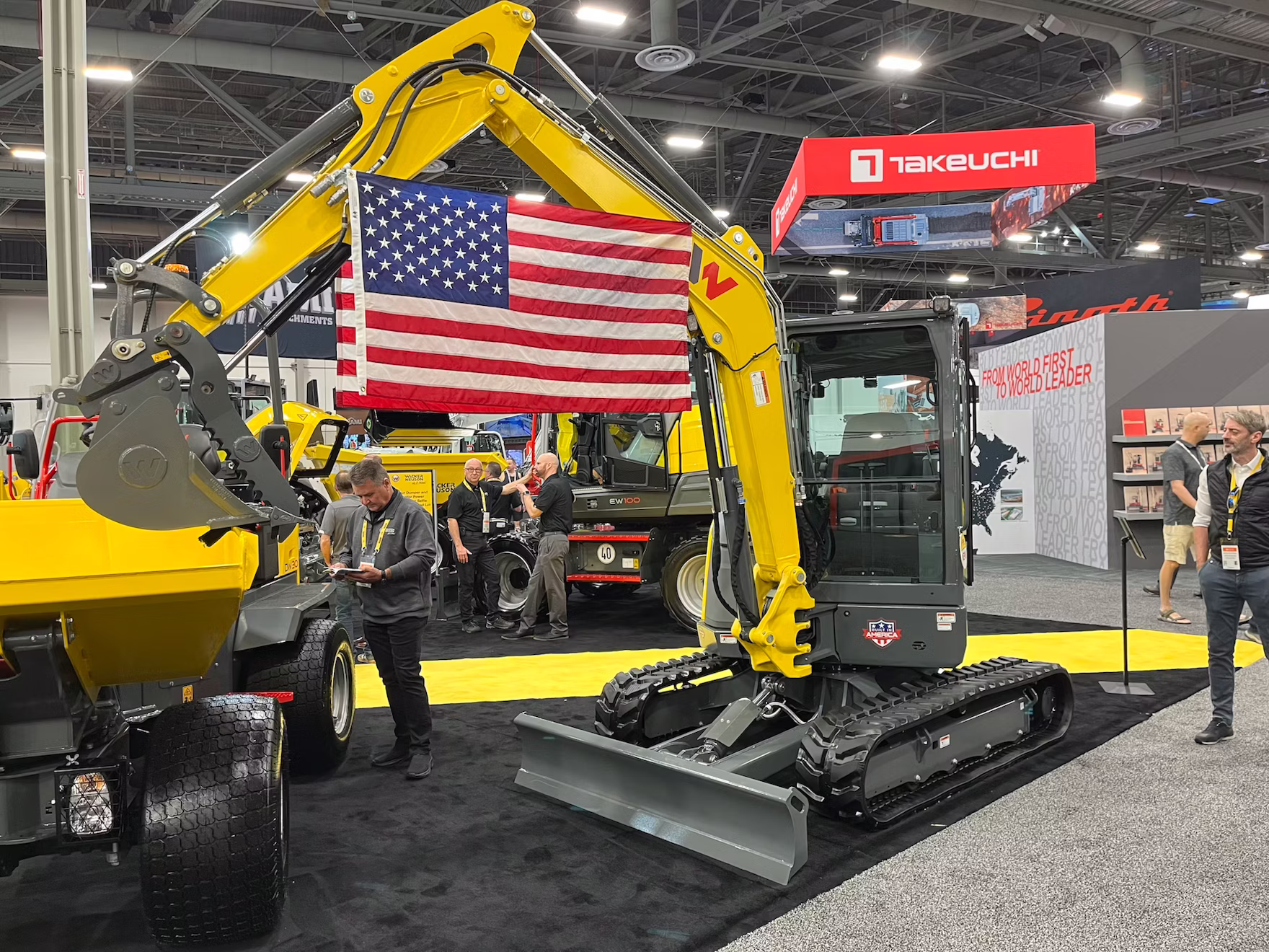 Yellow Takeuchi excavator with American flag at industrial trade show exhibition