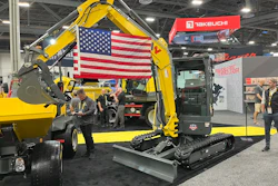 Yellow Takeuchi excavator with American flag at industrial trade show exhibition
